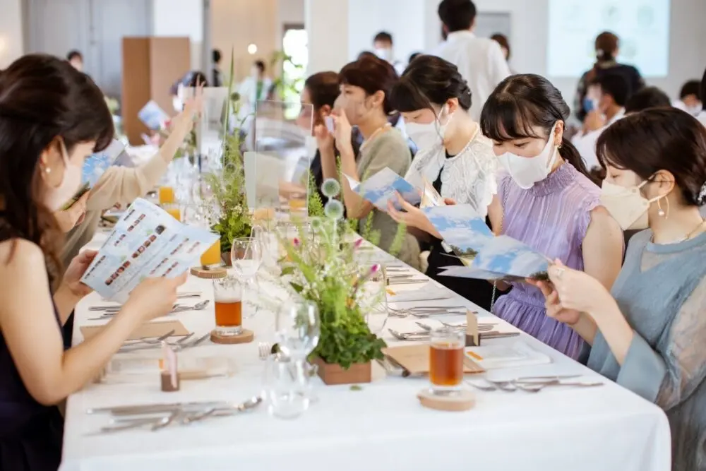 結婚式当日、会話しながらペーパーを読むゲスト